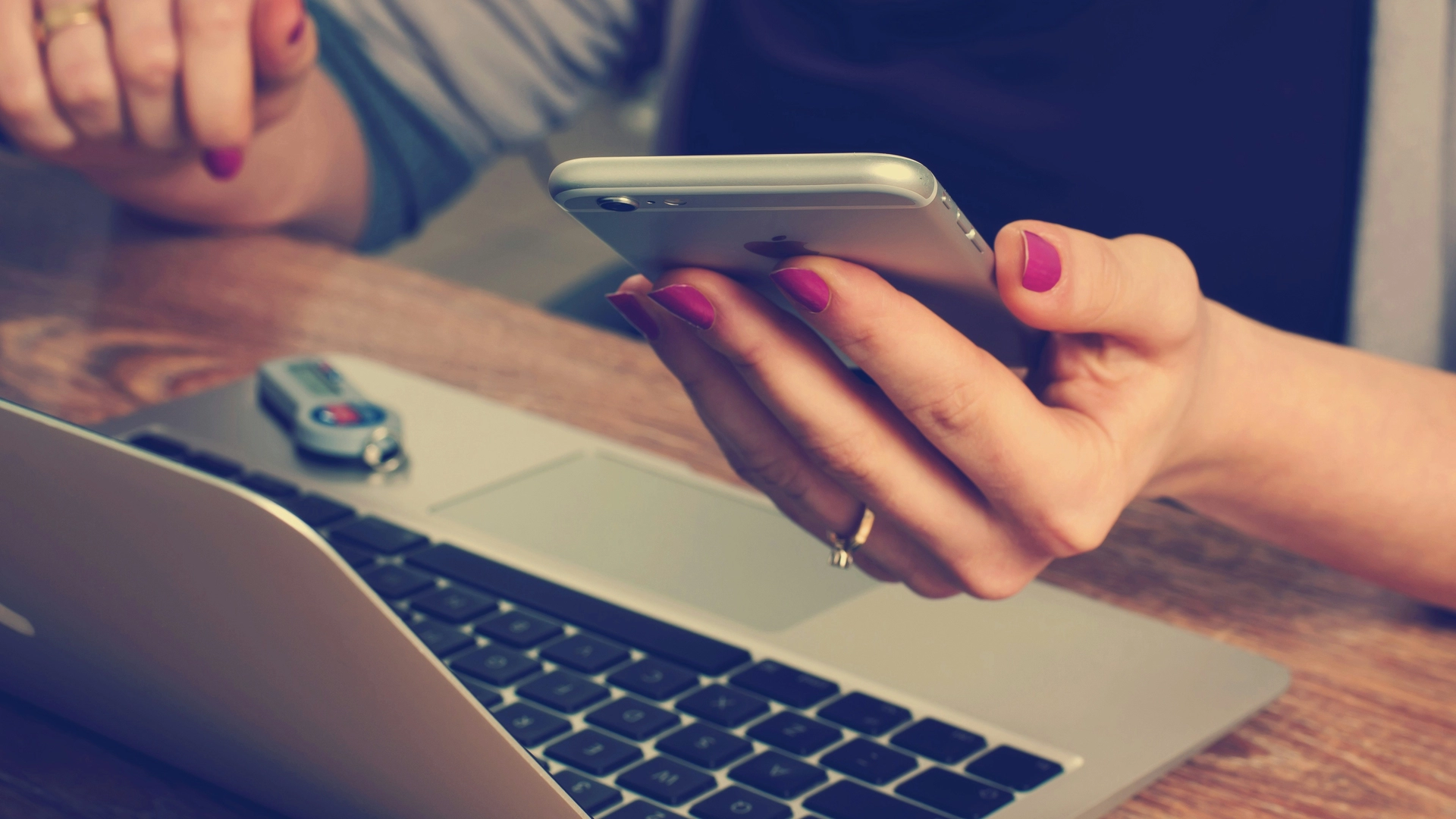 hand holding a phone near a laptop